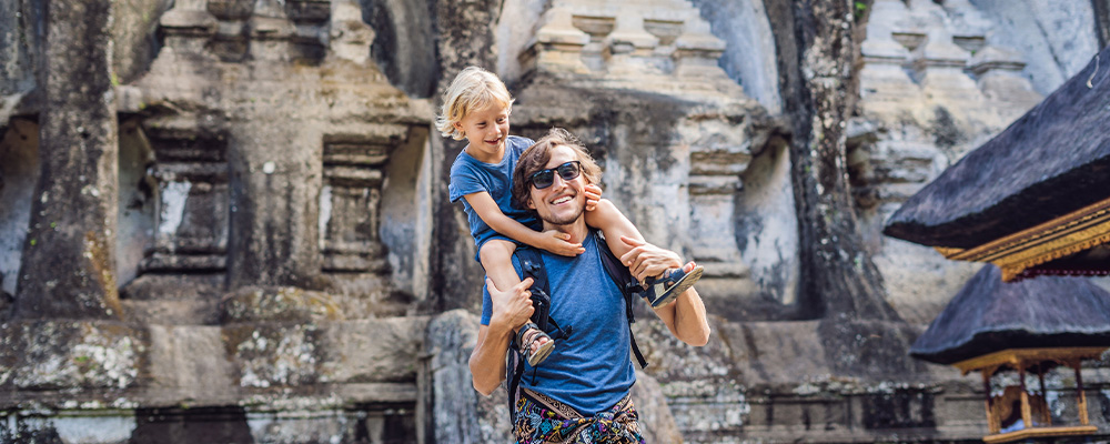 Father with son on shoulders in front of temple