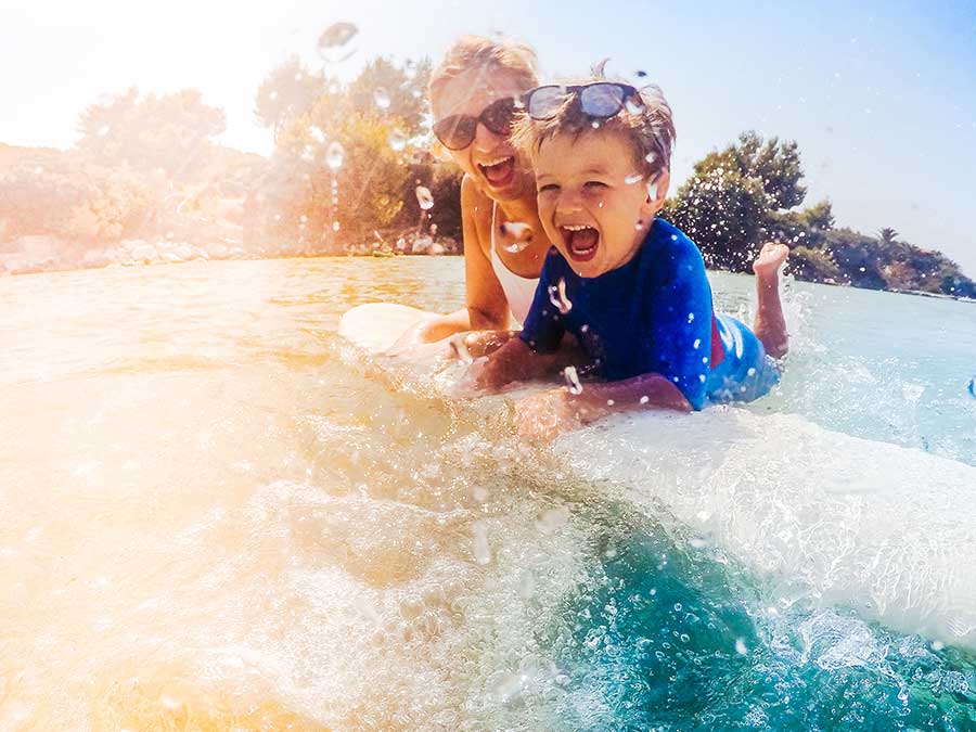 Mum and boy body boarding by the water